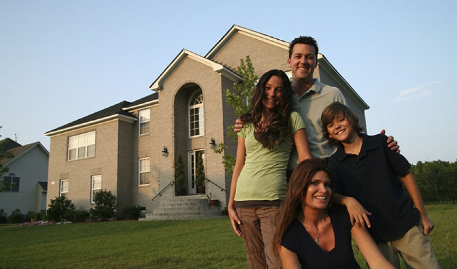 Family smiling, standing outside their home